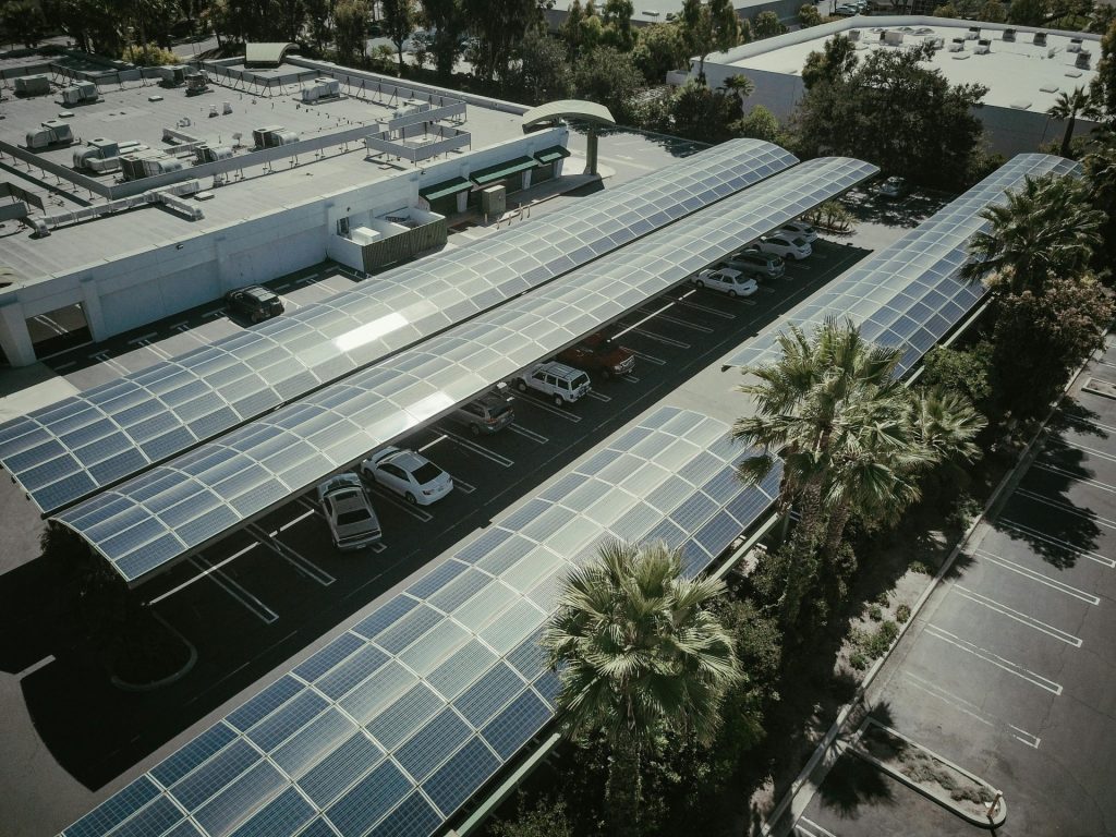 Luftaufnahme eines Parkplatzes mit Solarpanel-Überdachungen, die die Nutzung sauberer Energie demonstrieren.